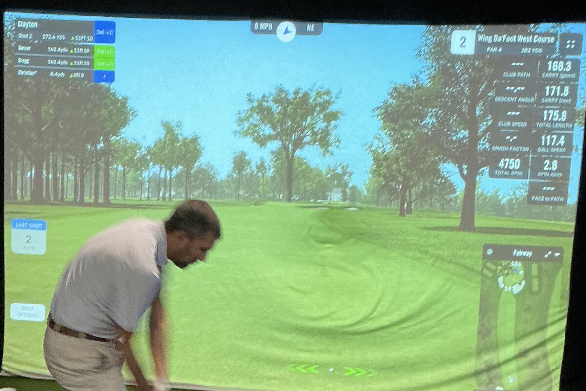 A simulated par 4 on the bay screen, with four players on the card and the carry, club speed and spin of the shot just hit.